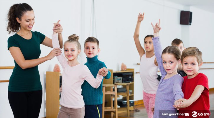 무용 연습실에서 아이들과 선생님이 협동하여 포즈를 취하고 있다