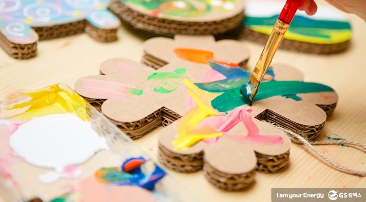 아이가 골판지로 만든 조형물에 물감을 칠하고 있다