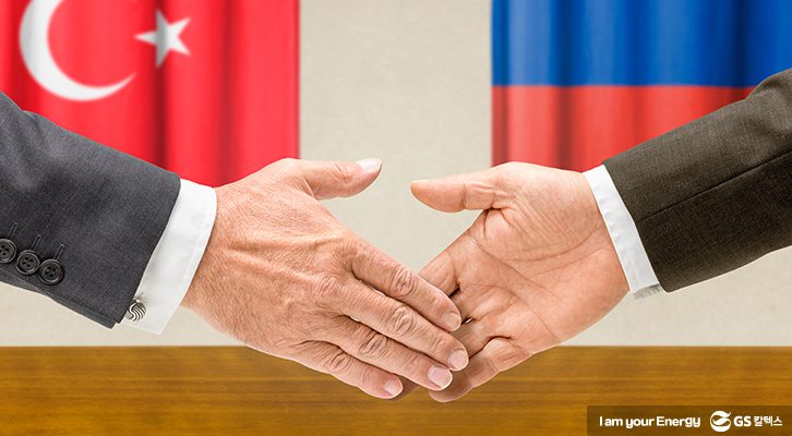 각국 국기 앞에서 악수하는 러시아와 터키 대표의 손을 클로즈업한 모습
