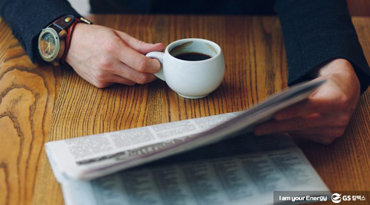 2018년 12월호 뉴스브리핑, 한 손에는 커피를 들고 한 손에는 신문지를 든 남자의 상체가 클로즈업 된 모습
