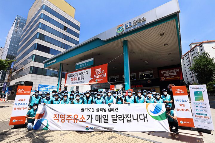 GS칼텍스 주유소 클리닝 캠페인에 참여한 사람들이 슬로건을 들고 기념사진을 찍는 모습